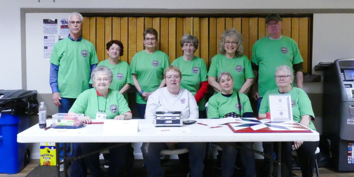 Group of volunteers in the Twin Tiers' green, volunteer shirts behind table before event begins.