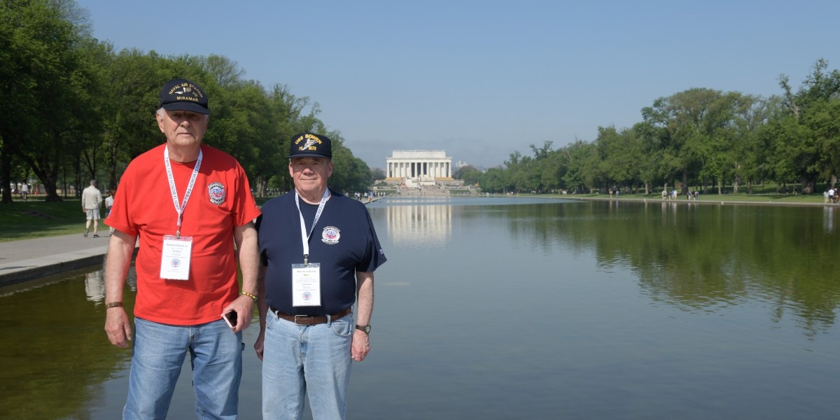 Veteran and Guardian pair standing in front of the Lincoln Memorial Reflecting Pool with the Lincoln Memorial in the distance.