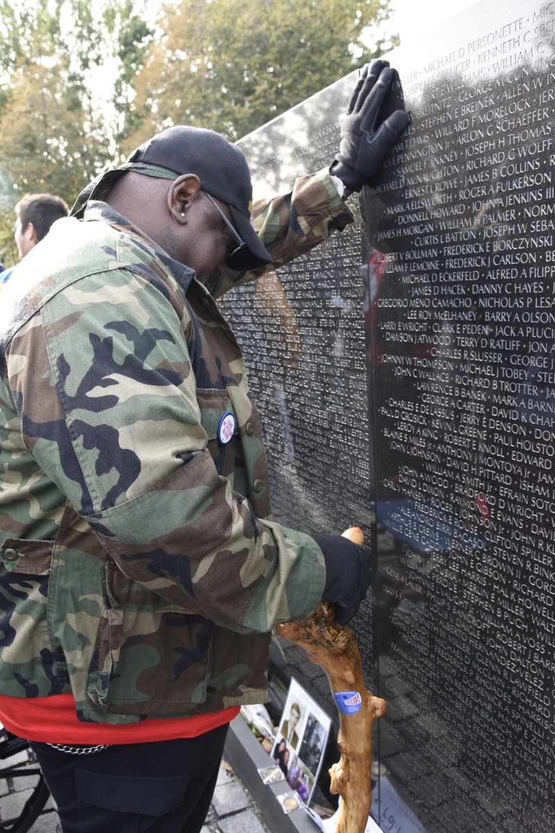 Veteran leaning on the Vietnam Memorial Wall with their hand.