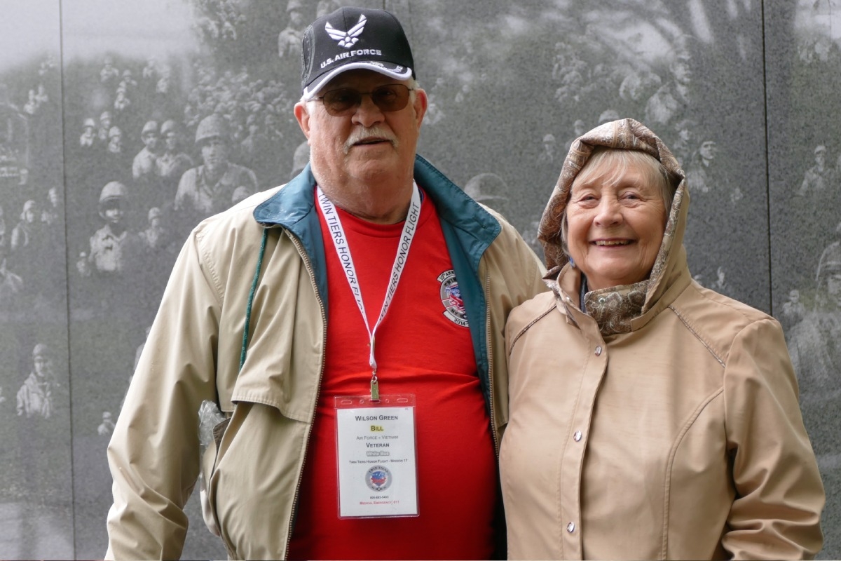 Veteran and Guardian standing together in front of the Korean Memorial Wall.